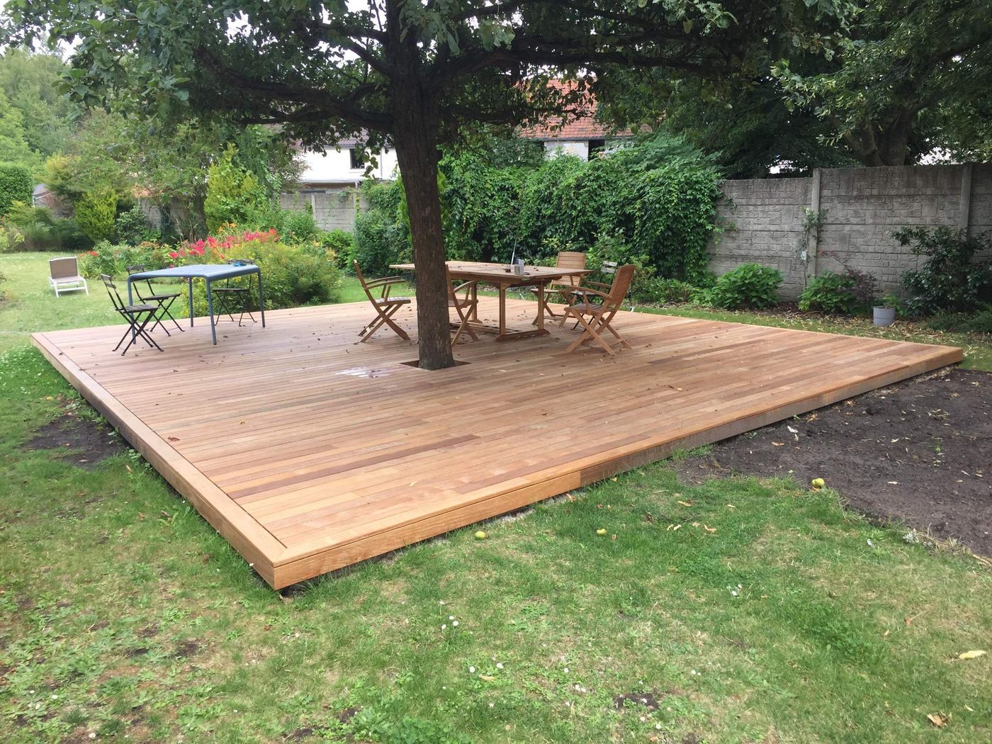 Grande terrasse en bois construite autour d'un arbre existant