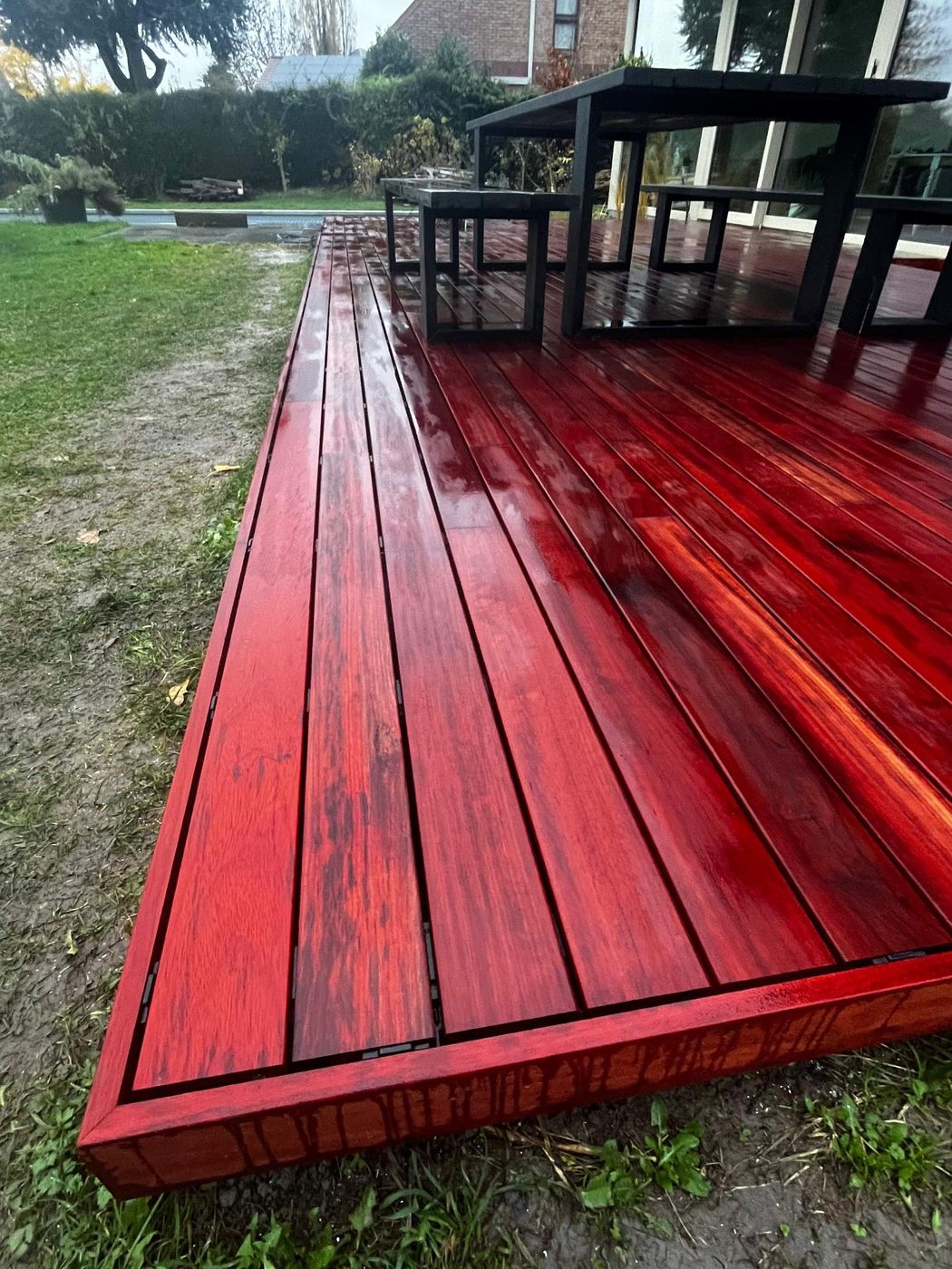 Parquet de jardin VETEDY en padouk et sa bordure, mobilier noir, après la pluie