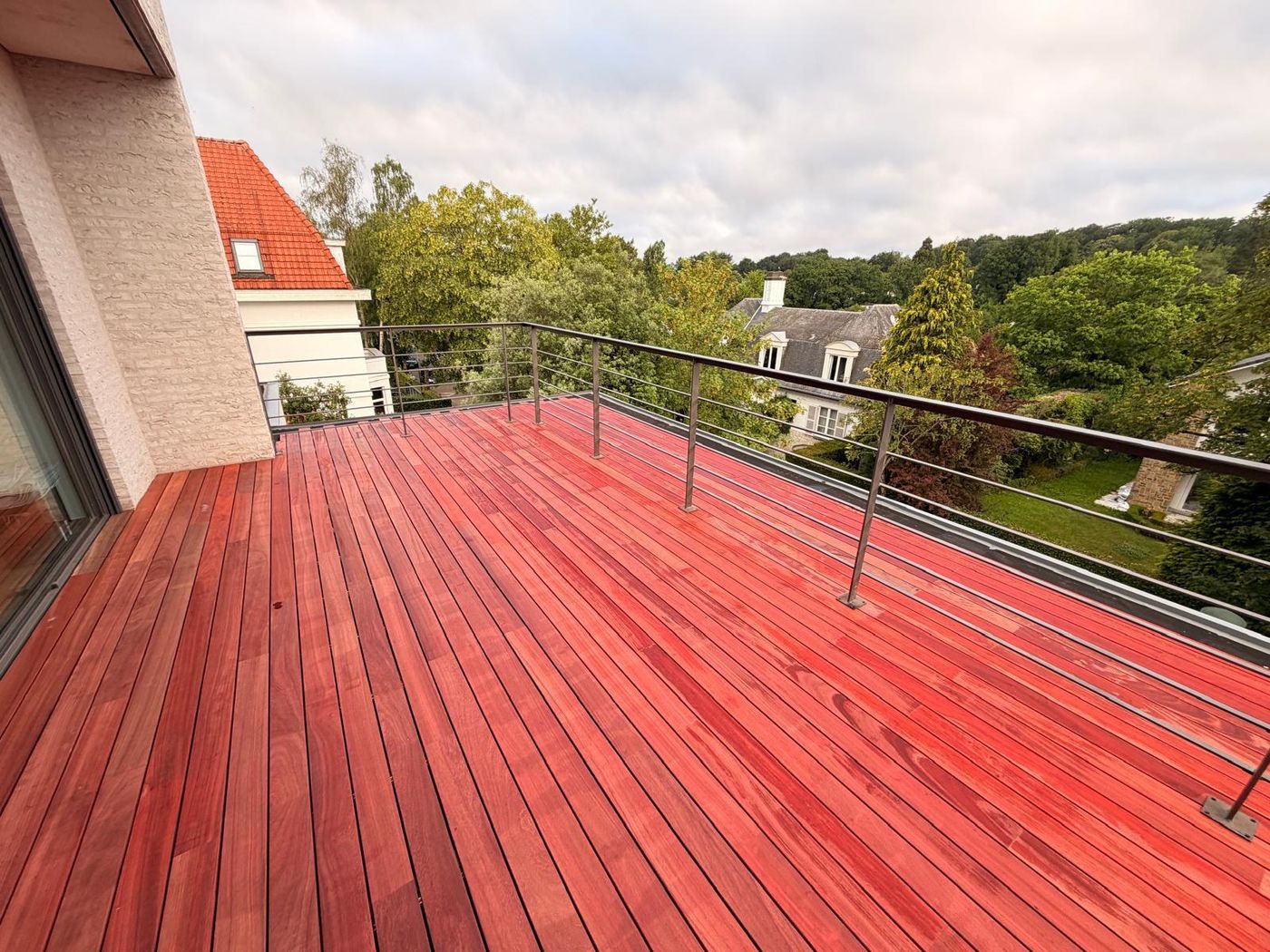 Toiture-terrasse en parquet de jardin VETEDY, padouk le long d'une façade claire